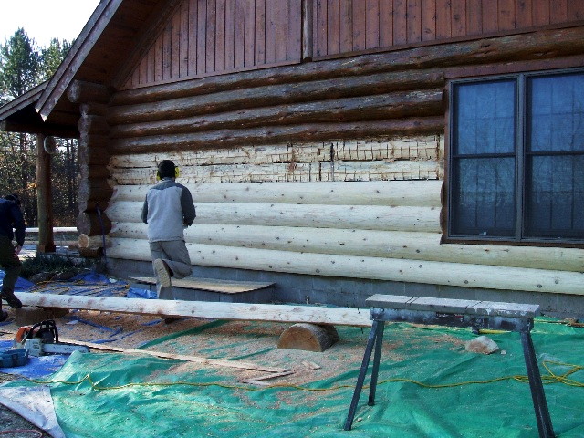 A log home being re-faced with half-logs.