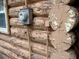 A log cabin with damaged peeling paint.