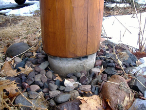 A log post correctly installed on a spacer to keep it off the ground and away from moisture.