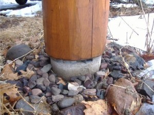 This is one solution to protect posts from rot. The spacer lifts the log off the ground and allows for ventilation around the log.